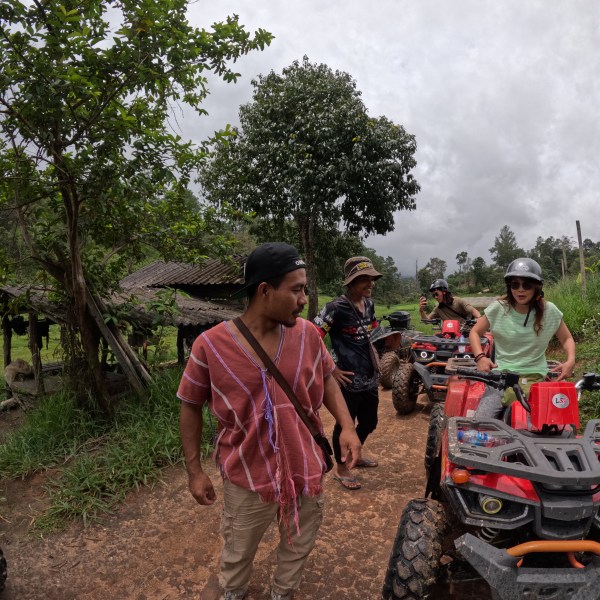 Group with quad bikes on a muddy path in a forested area.